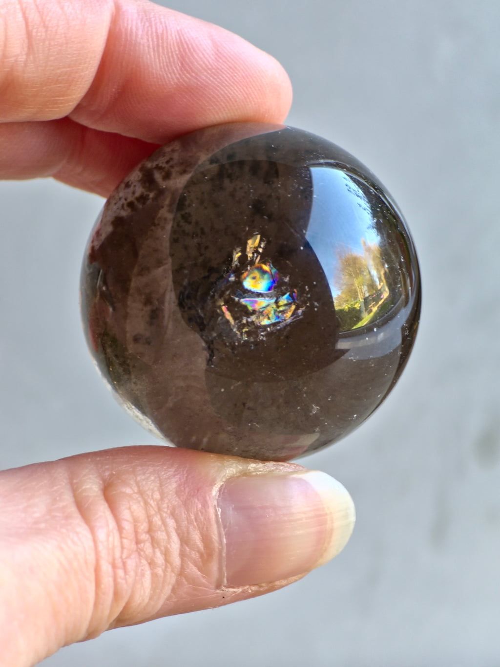 Smoky quartz sphere with green chlorite inclusions and rainbow